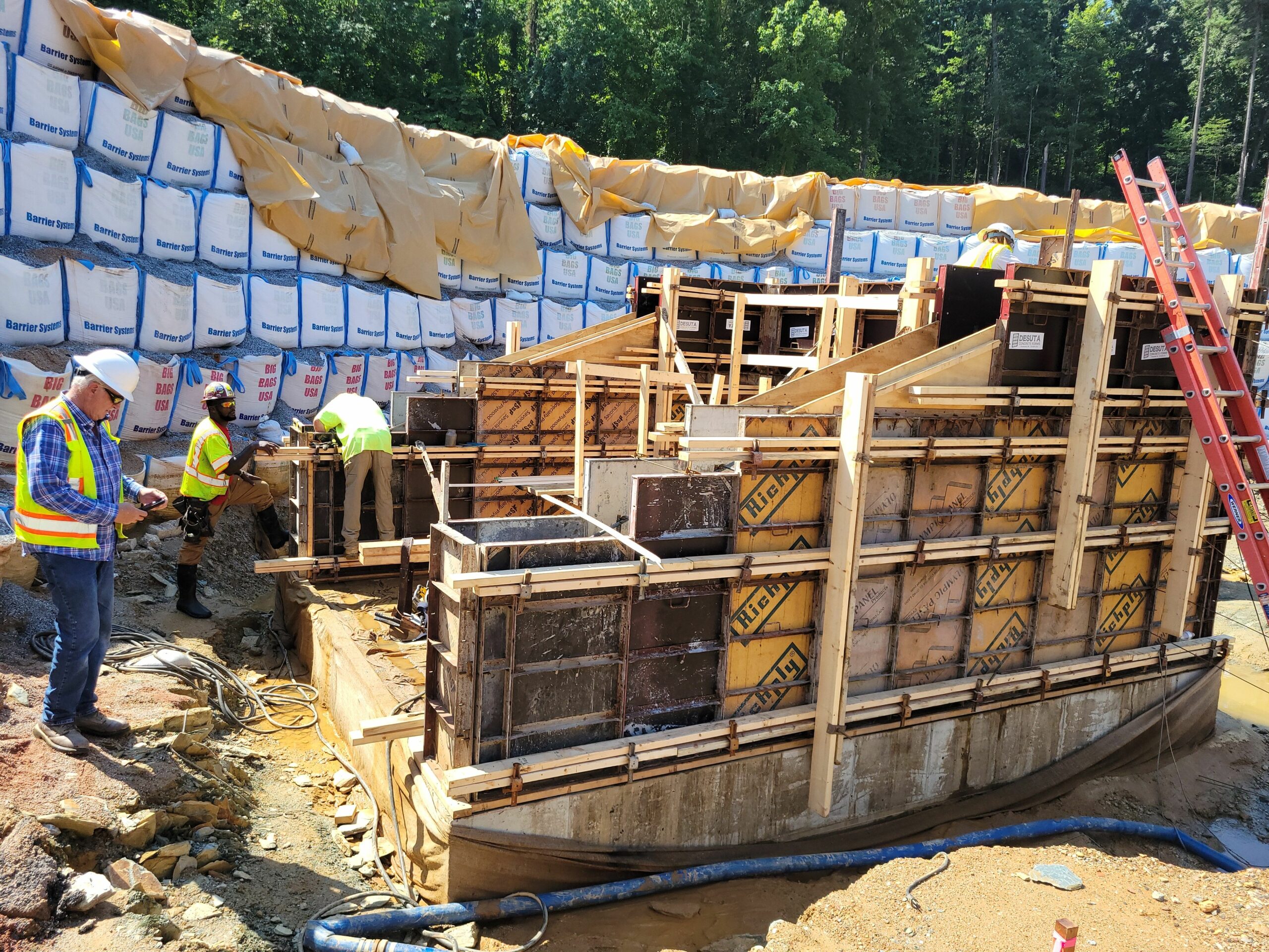 Work on the concrete foundations of the inlet and valve tower structures is being done, as well as removal of the earth from the left side of the downstream embankment. Pictured above is the 48″ diameter inlet pipe structure that is being formed on the bottom of the reservoir.