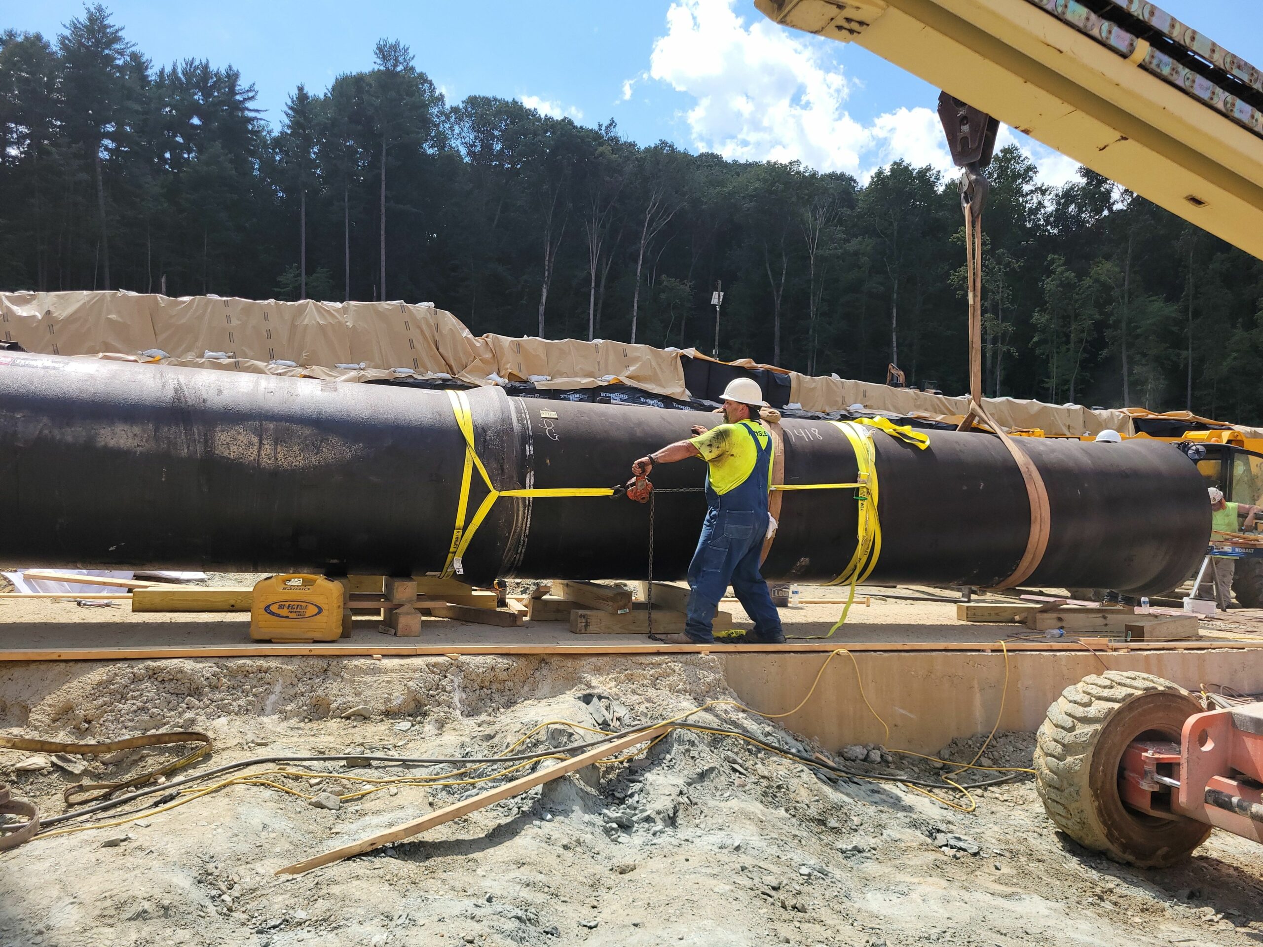 Two sections of 48-inch diameter DIP outlet pipe are being connected by Steve Clingan, KCI, from the valve tower to the spillway.