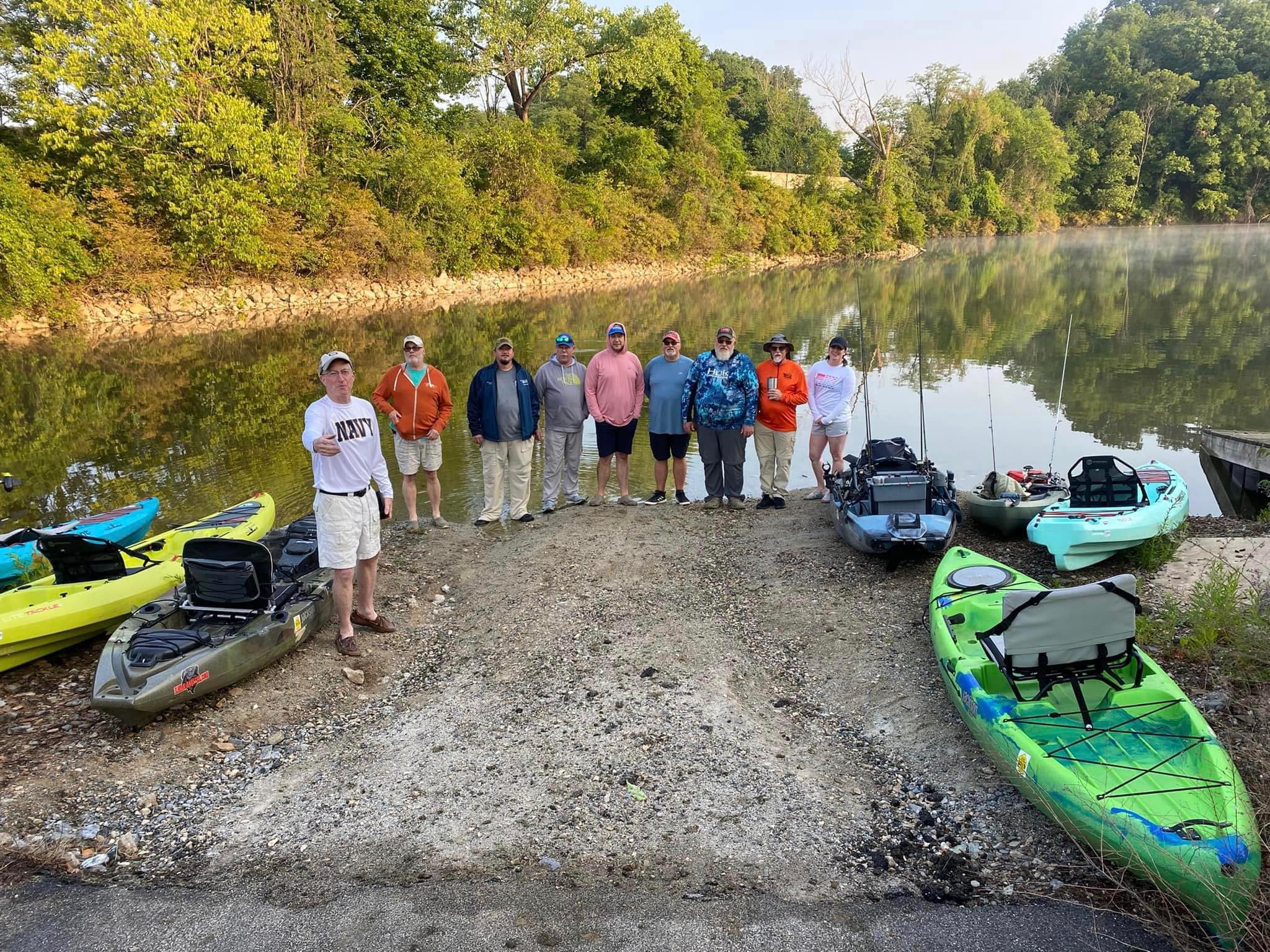 A group of people on the river bank preparing to kayak.