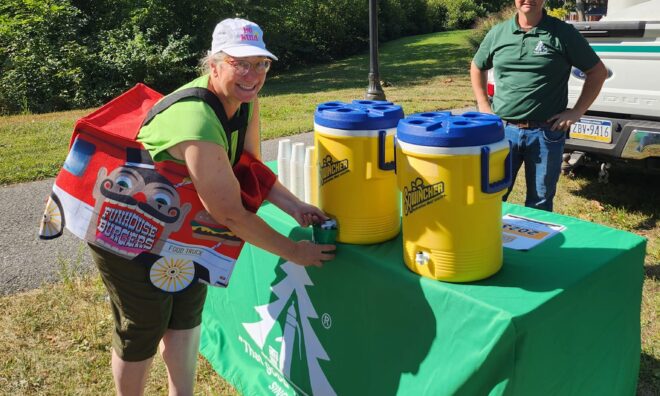 Man and woman standing near the water station for drinks at a festival.