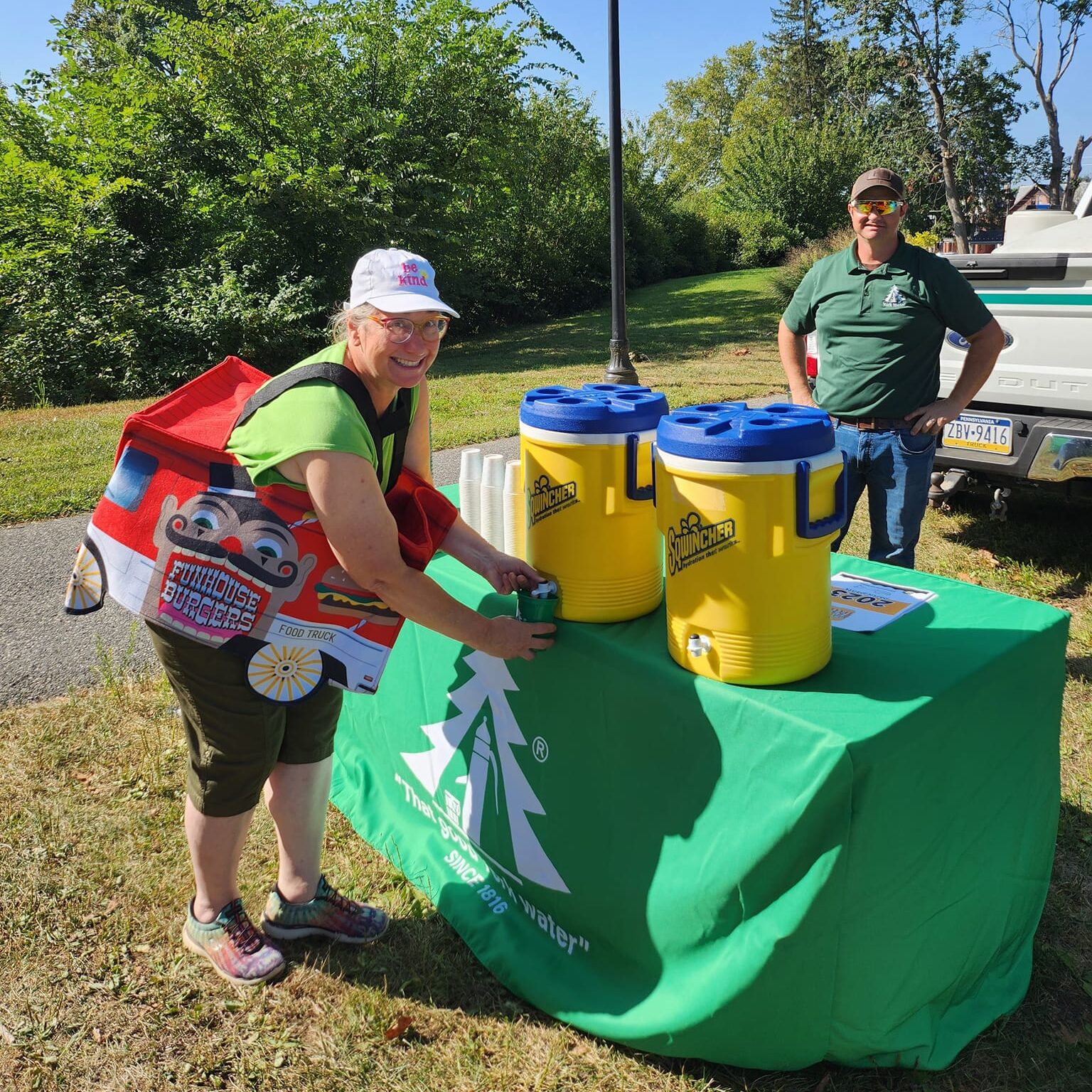 Man and woman standing near the water station for drinks at a festival.