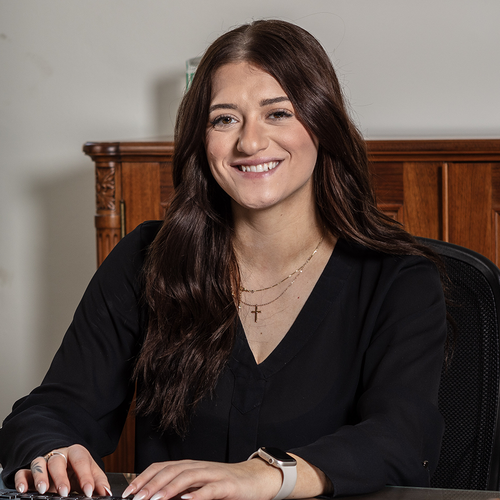 An employee sits at her desk and smiles.