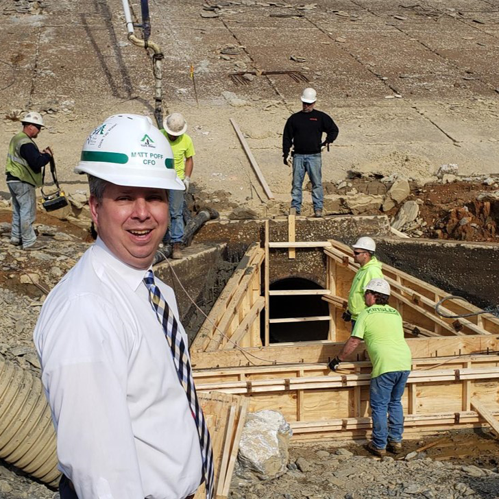 Staff members in hard hats looking at a tunnel in the construction of the dam.