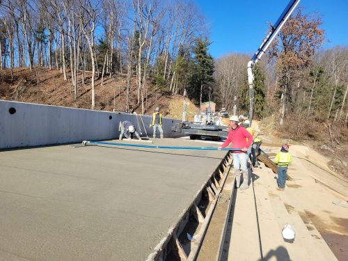 Group of construction workers smooth concrete on dam.