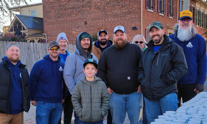 Employees and family members of York Water are pictured at a table filled with little cups of water outside.