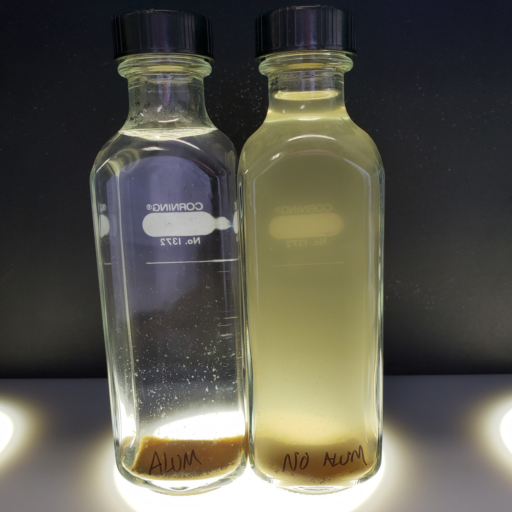 Two bottles of water samples comparing water with aluminum and without aluminum.