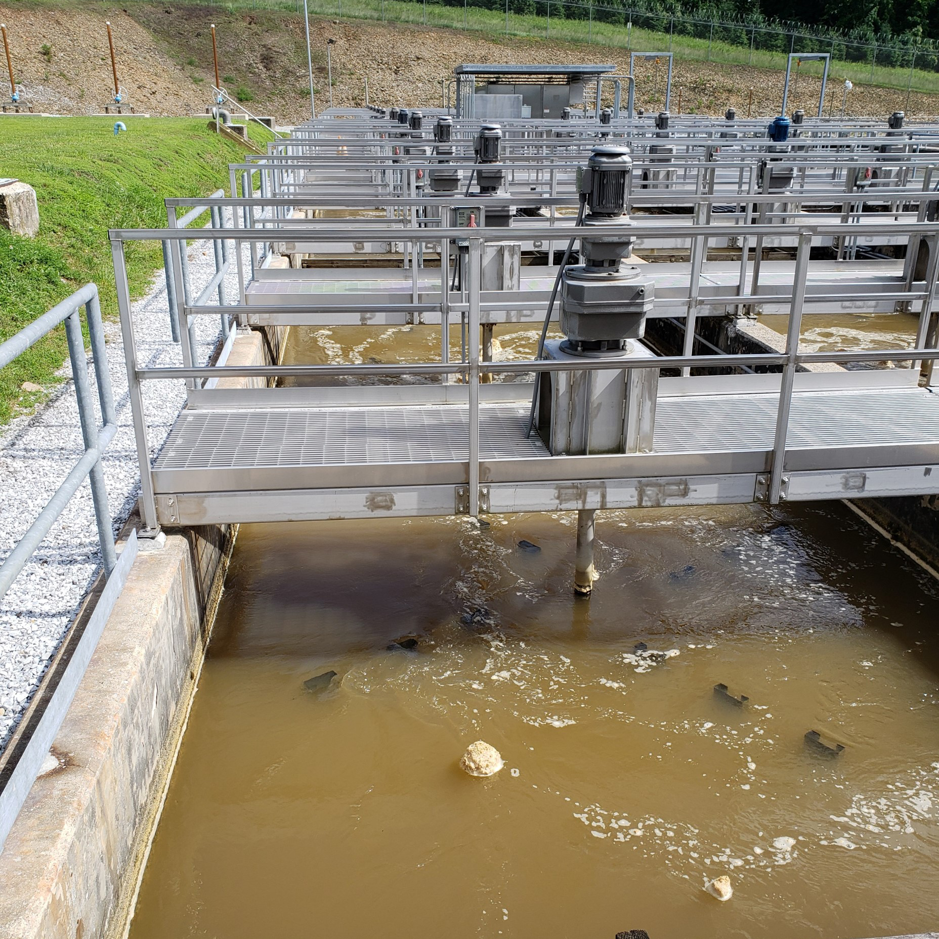Flocculation tanks are shown. A foamy substance forms on top of cloudy water.