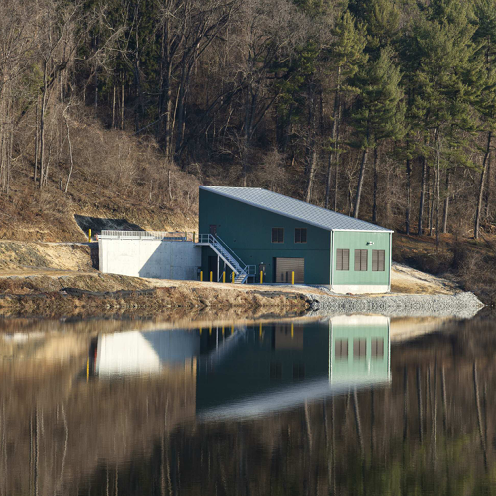 The exterior of the Lake Redman Pumping Station is pictured. It is reflected in the lake water.
